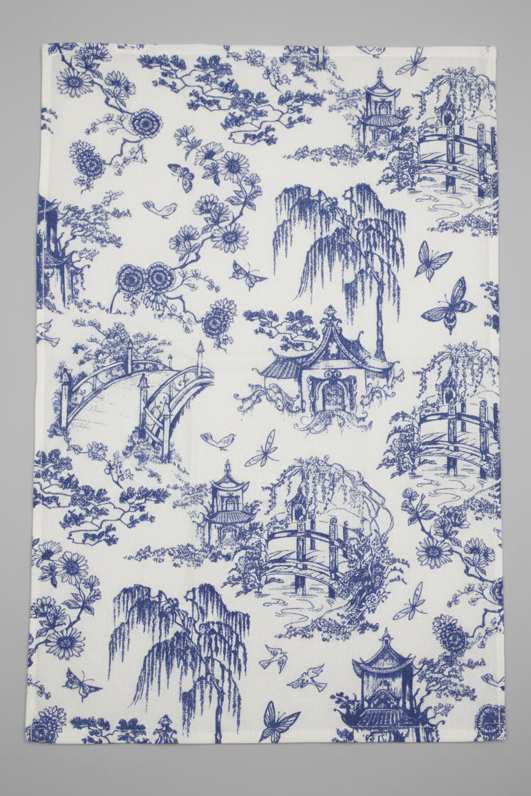 Towel fully opened, featuring a classic blue and white toile pattern of pagodas, flowers, and butterflies, laid flat on a gray surface.