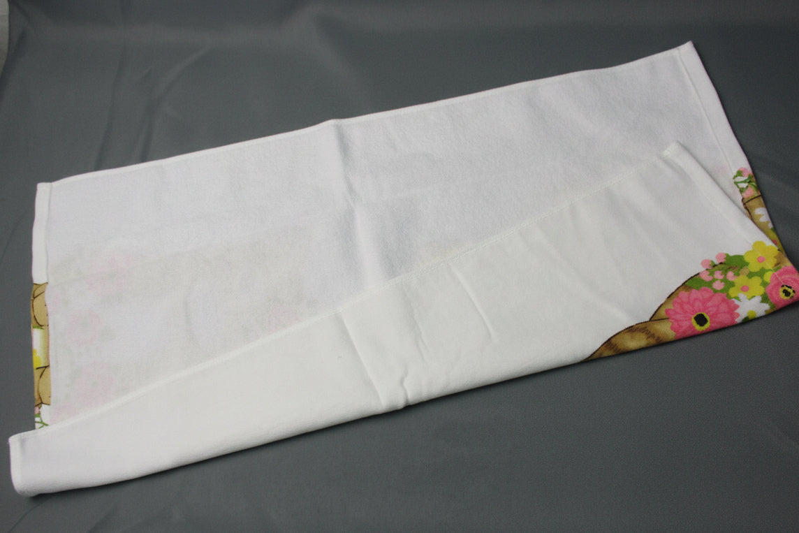 Back side of towel, showing a colorful floral pattern along the edges, laid on a dark gray surface.