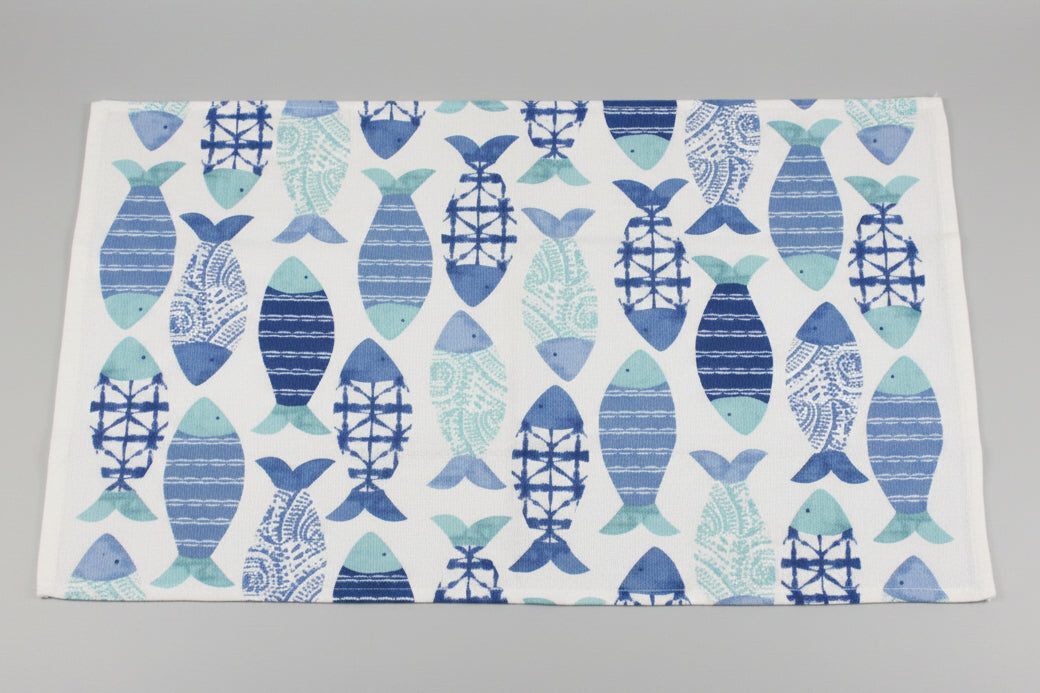 Towel fully opened, featuring a repeating pattern of stylized fish in various blue and teal shades on a white background, laid flat on a gray surface.