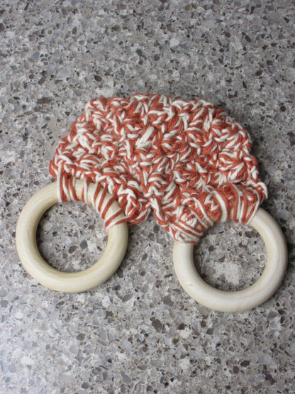 A handmade Kitchen towel Holder made of 100% Cotton Yarn in Rust and Ivory Color with two cream-colored wooden rings, shown on a speckled gray countertop.