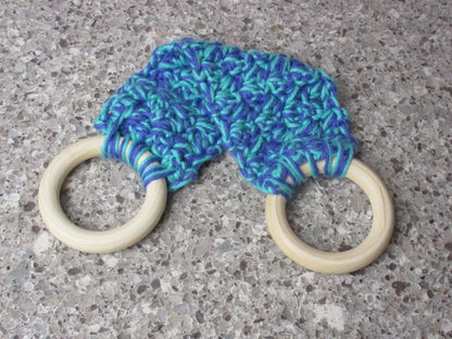 A handmade Kitchen towel Holder made of 100% Cotton Yarn in Cobalt Blue and Med. Teal Colors with two cream-colored wooden rings, shown on a speckled gray countertop.