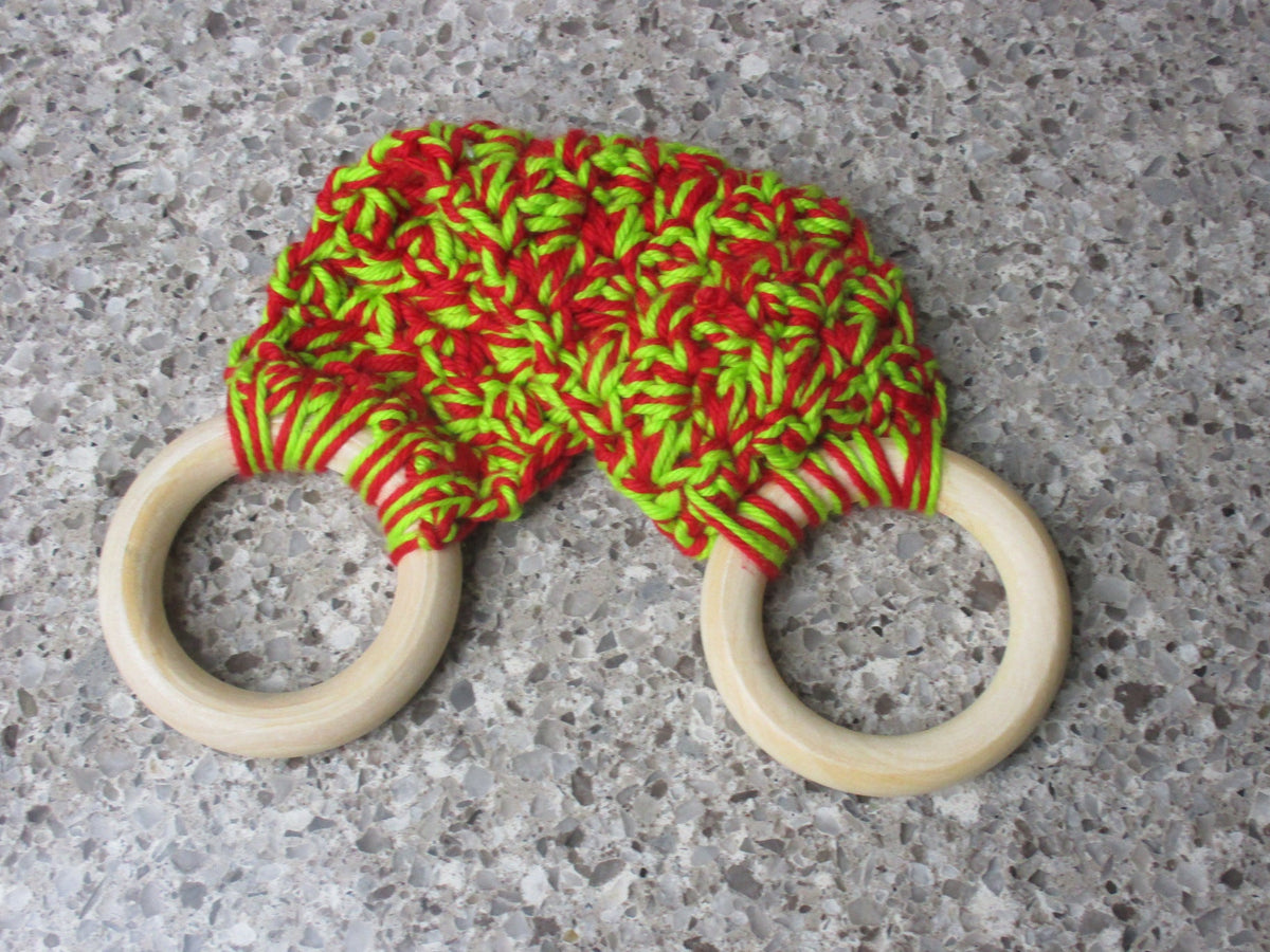 A handmade Kitchen towel Holder made of 100% Cotton Yarn in Bright Red and Lime Green Colors with two cream-colored wooden rings, shown on a speckled gray countertop.