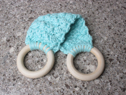 A handmade Kitchen towel Holder made of 100% Cotton Yarn in Med. Aqua Color with two cream-colored wooden rings, shown on a speckled gray countertop.