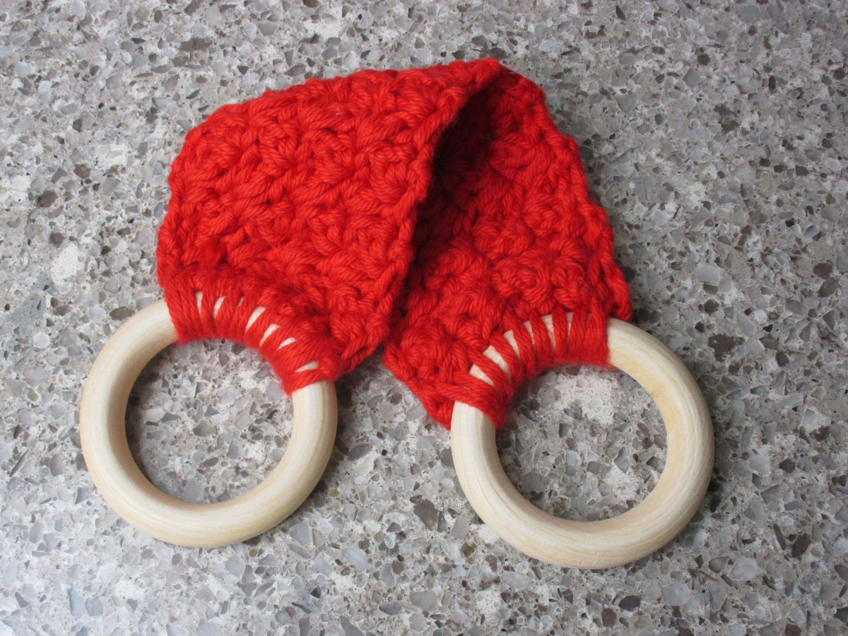 A handmade Kitchen towel Holder made of 100% Cotton Yarn in Bright Red Color with two cream-colored wooden rings, shown on a speckled gray countertop.