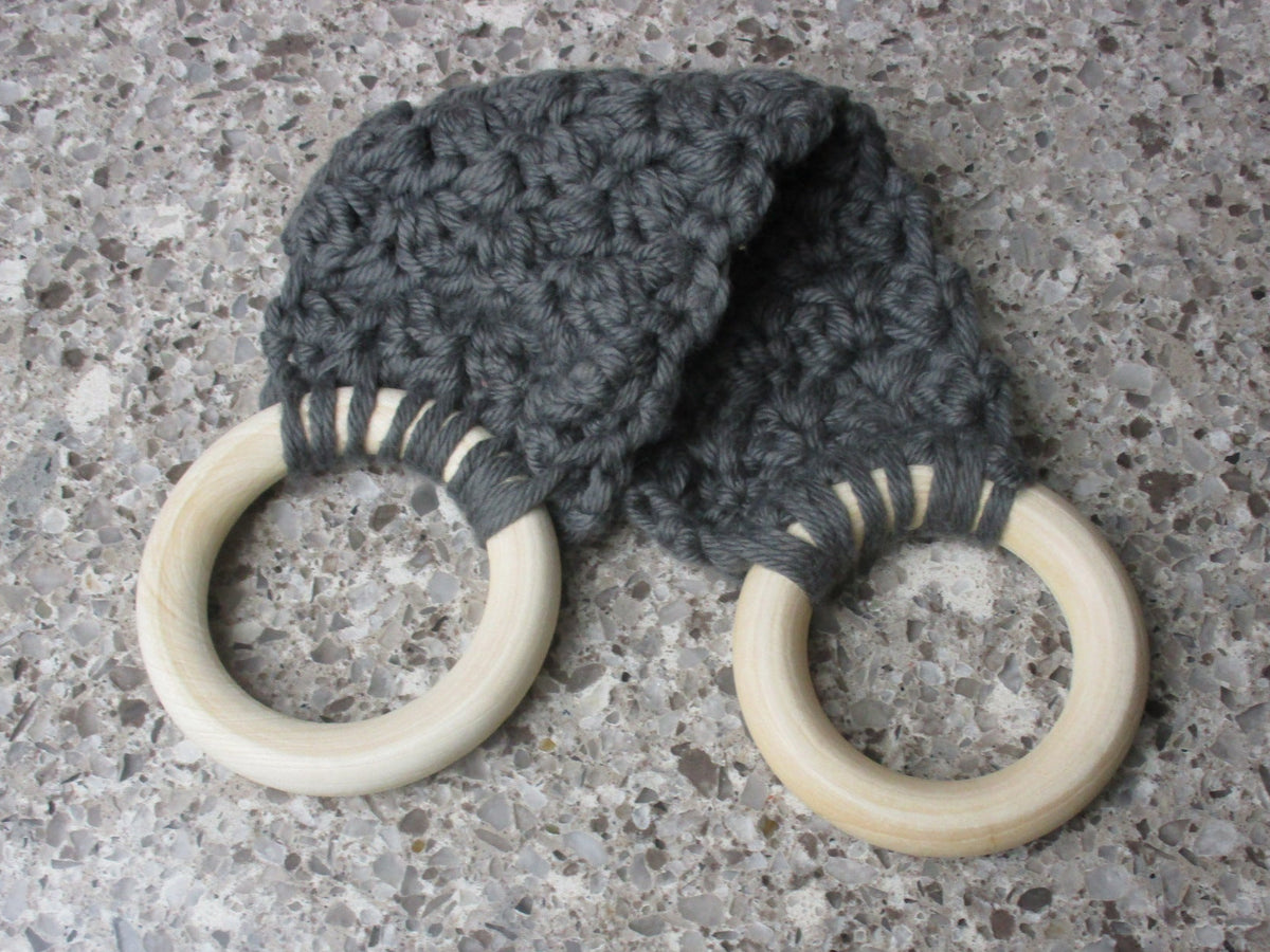 A handmade Kitchen towel Holder made of 100% Cotton Yarn in Dk. Gray Color with two cream-colored wooden rings, shown on a speckled gray countertop.