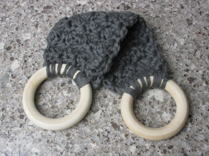A handmade Kitchen towel Holder made of 100% Cotton Yarn in Dk. Gray Color with two cream-colored wooden rings, shown on a speckled gray countertop.
