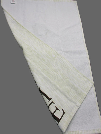Back side of towel with a subtle textured pattern and a dark brown printed logo, laid out on a gray surface.
