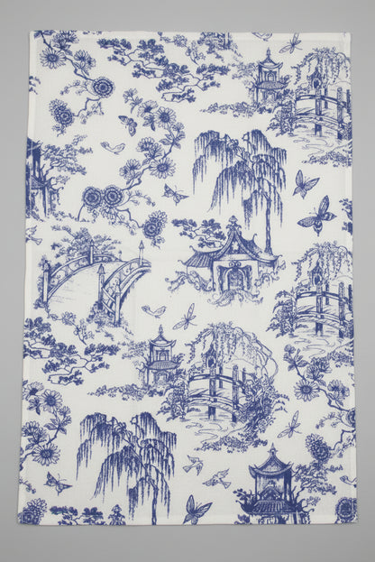 Towel fully opened, featuring a classic blue and white toile pattern of pagodas, flowers, and butterflies, laid flat on a gray surface.