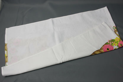 Back side of towel, showing a colorful floral pattern along the edges, laid on a dark gray surface.
