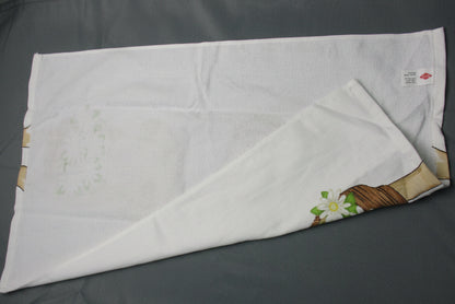 Back side of towel with a small floral and leaf print in the bottom right corner, folded over on a dark gray fabric background.