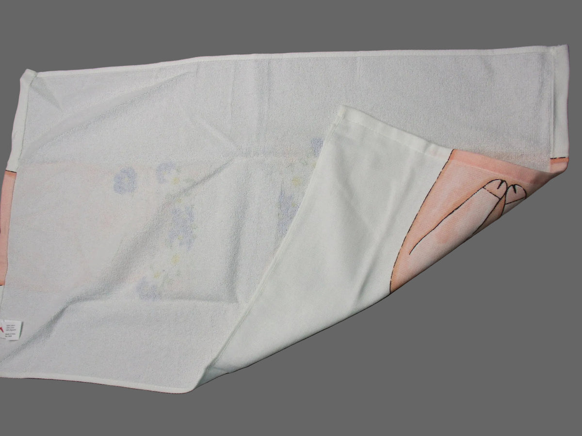 Back side of towel with a light pink border and a faint pastel floral pattern, folded diagonally on a dark gray surface.