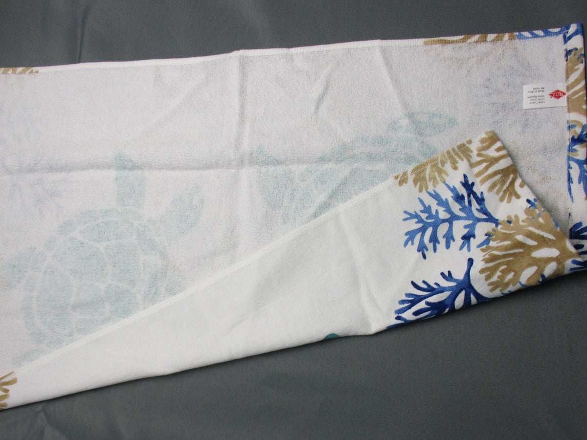 Back side of towel with a blue and gold coral print, laid flat on a dark gray background.