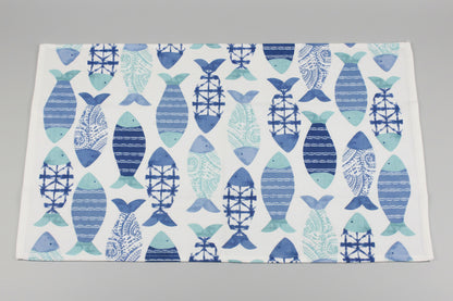 Towel fully opened, featuring a repeating pattern of stylized fish in various blue and teal shades on a white background, laid flat on a gray surface.