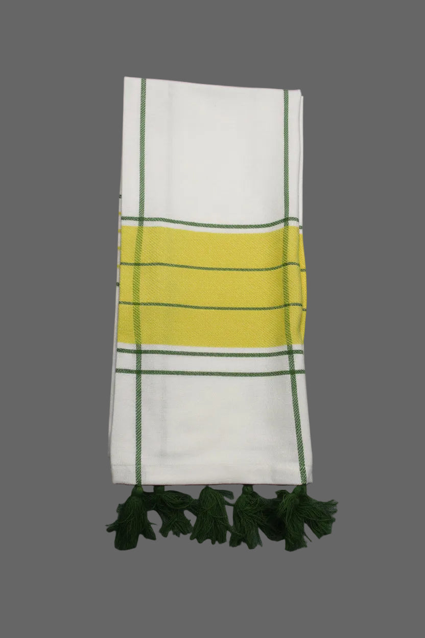A folded white towel with a central yellow stripe bordered by green, accented by green stripes and matching green tassels on the right, laid flat on a gray textured background.