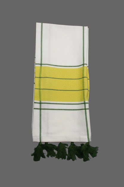A folded white towel with a central yellow stripe bordered by green, accented by green stripes and matching green tassels on the right, laid flat on a gray textured background.